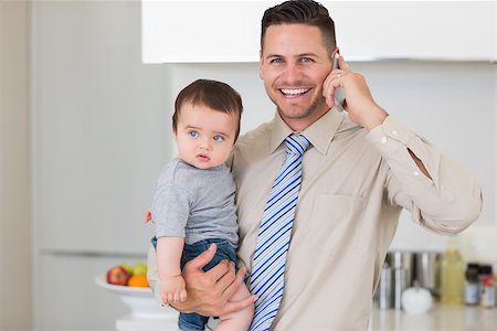 simsearch:6102-08858419,k - Portrait of happy businessman carrying baby boy while while using cellphone at home Stock Photo - Budget Royalty-Free & Subscription, Code: 400-07335638