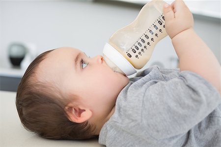 simsearch:400-07329323,k - Side view of lovely baby boy drinking milk while lying on kitchen counter Foto de stock - Royalty-Free Super Valor e Assinatura, Número: 400-07335702