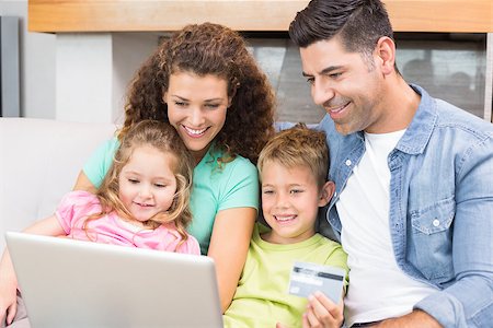 simsearch:693-06435973,k - Happy family sitting on sofa using laptop together to shop online at home in living room Stock Photo - Budget Royalty-Free & Subscription, Code: 400-07336282