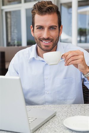 drinking coffee on patio - Smiling businessman working with laptop drinking coffee in patio of restaurant Stock Photo - Budget Royalty-Free & Subscription, Code: 400-07337275