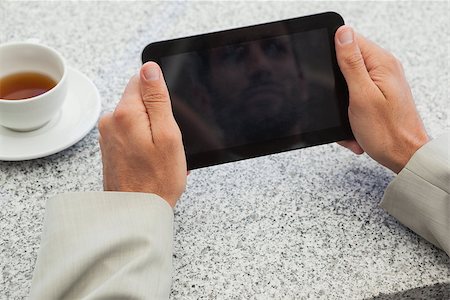 Businessman holding small tablet at table in patio of restaurant Photographie de stock - Aubaine LD & Abonnement, Code: 400-07337300