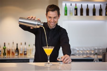 drink shaker - Smiling bartender pouring yellow cocktail into glass at the bar Stock Photo - Budget Royalty-Free & Subscription, Code: 400-07337381