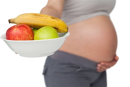 Pregnant woman showing fruit bowl to camera on white background Stock Photo - Budget Royalty-Free & Subscription, Code: 400-07337429