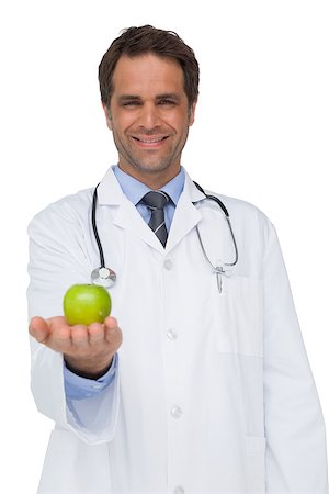 simsearch:400-04217553,k - Happy doctor smiling and holding apple to camera on white background Foto de stock - Royalty-Free Super Valor e Assinatura, Número: 400-07337433