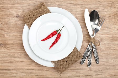 simsearch:400-07331603,k - Red chili peppers on plate and silverware set on wooden table Foto de stock - Super Valor sin royalties y Suscripción, Código: 400-07337794