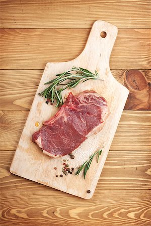 steak and fries - Raw sirloin steak with rosemary and spices on cutting board over wooden table Photographie de stock - Aubaine LD & Abonnement, Code: 400-07337847