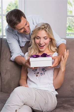 simsearch:6109-07601570,k - Smiling young man surprising cheerful woman with a gift box at home Stockbilder - Microstock & Abonnement, Bildnummer: 400-07339243