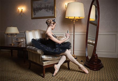 Ballerina in black tutu sitting in armchair in front of mirror and taking self portrait with camera on her cell phone Photographie de stock - Aubaine LD & Abonnement, Code: 400-07330955