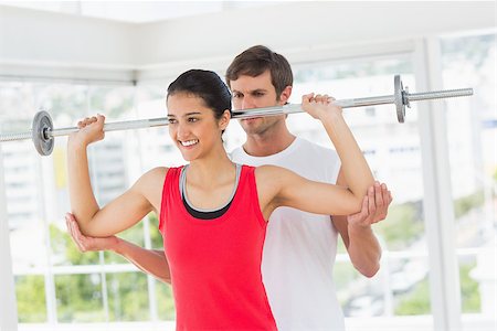 simsearch:400-07333355,k - Male trainer helping happy young fit woman to lift the barbell in the gym Stock Photo - Budget Royalty-Free & Subscription, Code: 400-07333065