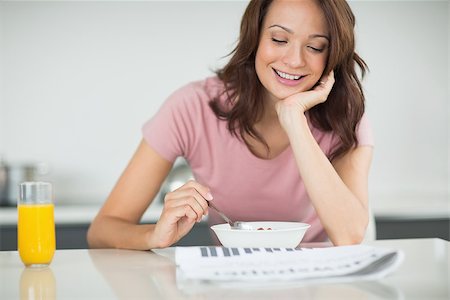 simsearch:400-06871178,k - Smiling young woman with a bowl of cereals reading newspaper in the kitchen at home Stock Photo - Budget Royalty-Free & Subscription, Code: 400-07333450