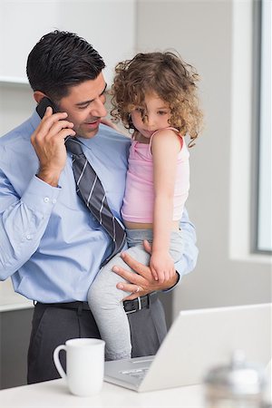 simsearch:6102-08942235,k - Smiling well dressed father using cellphone while carrying his little daughter in the kitchen at home Stockbilder - Microstock & Abonnement, Bildnummer: 400-07333518