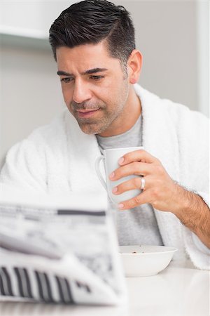 simsearch:6113-07790487,k - Serious casual man with coffee cup reading newspaper in the kitchen at home Foto de stock - Royalty-Free Super Valor e Assinatura, Número: 400-07333534