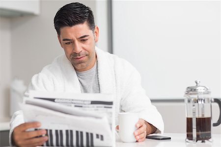 simsearch:6113-07790487,k - Serious casual man with coffee cup reading newspaper in the kitchen at home Foto de stock - Royalty-Free Super Valor e Assinatura, Número: 400-07333532