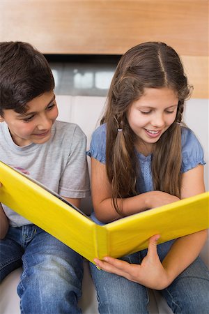Smiling young siblings looking at photo album on sofa in the living room at home Stock Photo - Budget Royalty-Free & Subscription, Code: 400-07333675