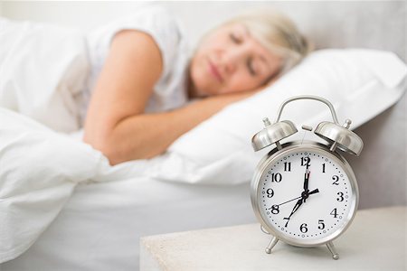 Blurred mature woman sleeping in bed with alarm clock in foreground at bedroom Stock Photo - Budget Royalty-Free & Subscription, Code: 400-07333707