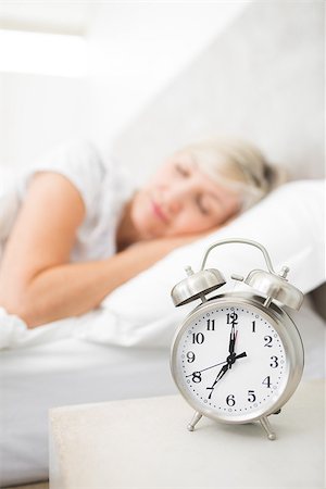 Blurred mature woman sleeping in bed with alarm clock in foreground at bedroom Stock Photo - Budget Royalty-Free & Subscription, Code: 400-07333708