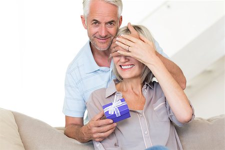 simsearch:6109-07601570,k - Portrait of a smiling mature man surprising woman with a gift on sofa at home Stockbilder - Microstock & Abonnement, Bildnummer: 400-07333879