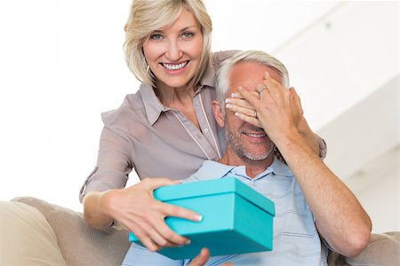 simsearch:6109-07601570,k - Portrait of a smiling woman surprising mature man with a gift on sofa at home Stockbilder - Microstock & Abonnement, Bildnummer: 400-07333884