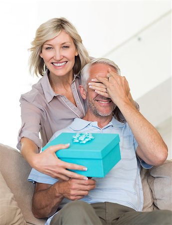 simsearch:6109-07601570,k - Portrait of a smiling woman surprising mature man with a gift on sofa at home Stockbilder - Microstock & Abonnement, Bildnummer: 400-07333885