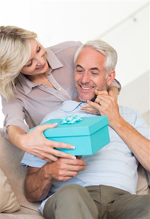 simsearch:6109-07601570,k - Portrait of a smiling woman surprising mature man with a gift on sofa at home Stockbilder - Microstock & Abonnement, Bildnummer: 400-07333886