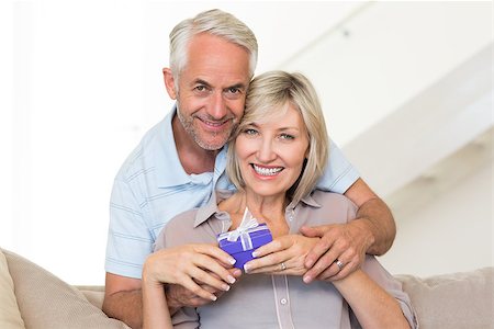 simsearch:6109-07601570,k - Portrait of a smiling mature man surprising woman with a gift on sofa at home Stockbilder - Microstock & Abonnement, Bildnummer: 400-07333881