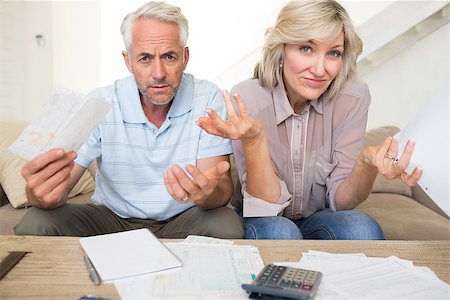Tensed mature man and woman with bills and calculator sitting on sofa at home Stock Photo - Budget Royalty-Free & Subscription, Code: 400-07333924