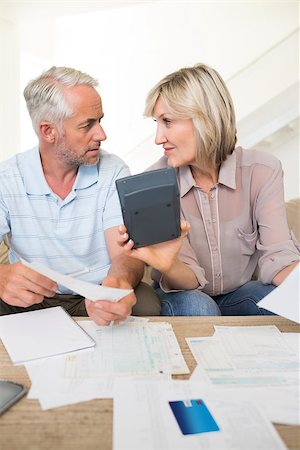 Concentrated mature man and woman with bills and calculator sitting on sofa at home Stock Photo - Budget Royalty-Free & Subscription, Code: 400-07333921