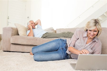 Mature woman using laptop while man on call in the living room at home Stock Photo - Budget Royalty-Free & Subscription, Code: 400-07333934