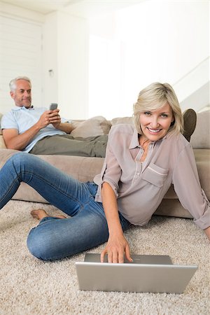 Mature woman using laptop while man text messaging in the living room at home Stock Photo - Budget Royalty-Free & Subscription, Code: 400-07333936