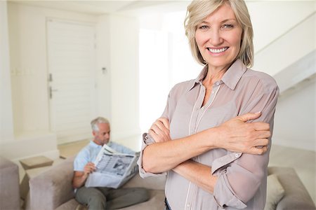 simsearch:400-07333928,k - Portrait of a smiling woman with man reading newspaper in background at home Stock Photo - Budget Royalty-Free & Subscription, Code: 400-07333954