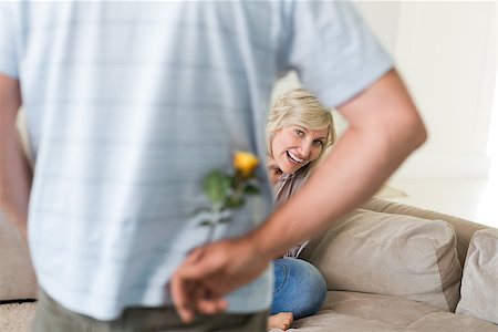 rear of house - Rear view of a man holding flower behind his back with woman sitting on couch at home Foto de stock - Super Valor sin royalties y Suscripción, Código: 400-07333960