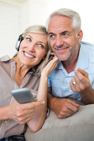 simsearch:614-07146178,k - Cheerful mature man and woman with headphones and cellphone sitting on sofa at home Foto de stock - Super Valor sin royalties y Suscripción, Código: 400-07333975