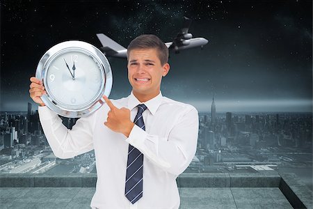 simsearch:400-07347006,k - Anxious businessman holding and showing a clock against balcony overlooking city Fotografie stock - Microstock e Abbonamento, Codice: 400-07344164