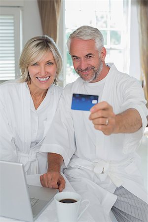 simsearch:400-07333971,k - Portrait of a happy mature couple holding out credit card at home Stock Photo - Budget Royalty-Free & Subscription, Code: 400-07344192