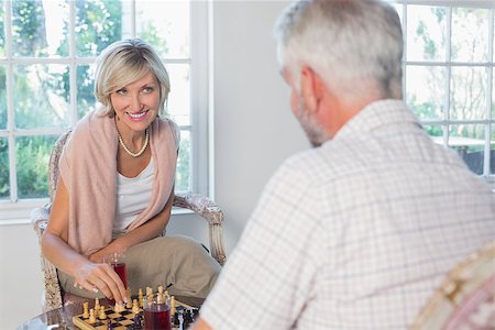 Smiling woman playing chess with man at home Stock Photo - Budget Royalty-Free & Subscription, Code: 400-07344252