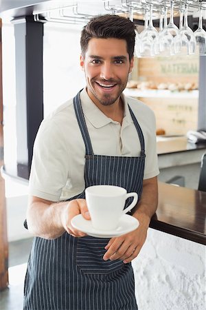 Young waiter smiling and holding cup of coffee at the café Stock Photo - Budget Royalty-Free & Subscription, Code: 400-07344900