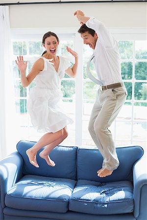 sofa jumping - Side view of a cheerful young couple jumping on couch at home Stock Photo - Budget Royalty-Free & Subscription, Code: 400-07346459