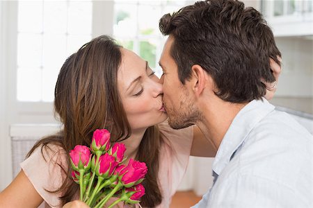 simsearch:400-07346120,k - Side view of a loving young couple kissing with flowers in hand at home Foto de stock - Super Valor sin royalties y Suscripción, Código: 400-07346464