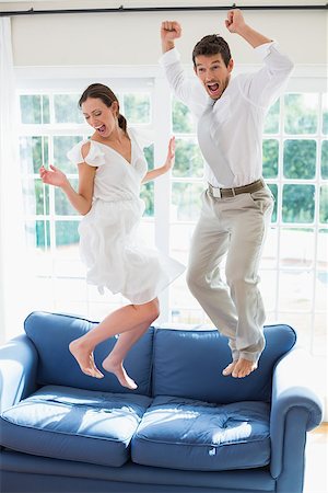 sofa jumping - Side view of a cheerful young couple jumping on couch at home Stock Photo - Budget Royalty-Free & Subscription, Code: 400-07346609