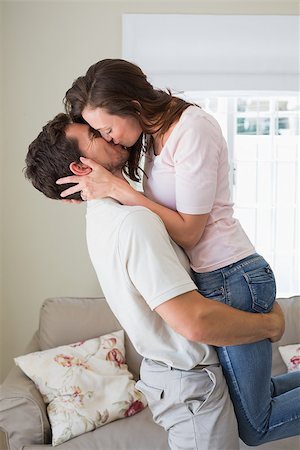 simsearch:400-07346120,k - Side view of a loving young couple kissing in the living room at home Foto de stock - Super Valor sin royalties y Suscripción, Código: 400-07347198