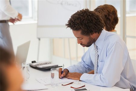 simsearch:400-04042753,k - Side view of a young businessman writing notes in meeting at the office Photographie de stock - Aubaine LD & Abonnement, Code: 400-07340699