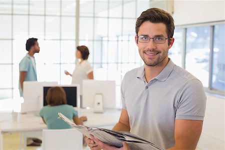 Portrait of a young businessman reading newspaper with colleagues in meeting in background at the office Photographie de stock - Aubaine LD & Abonnement, Code: 400-07341494