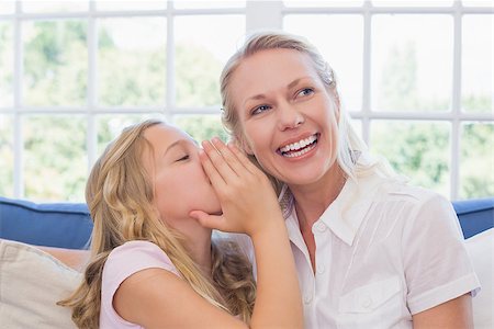 Little girl sharing secret with mother on sofa at home Stock Photo - Budget Royalty-Free & Subscription, Code: 400-07341605