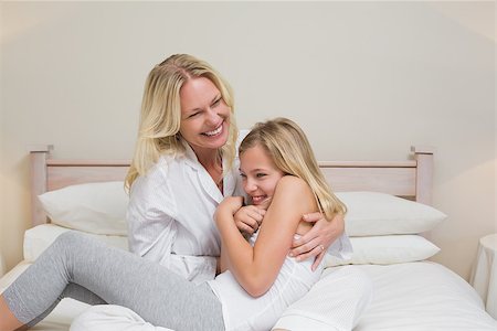 Happy woman tickling daughter in bed at home Foto de stock - Super Valor sin royalties y Suscripción, Código: 400-07341786