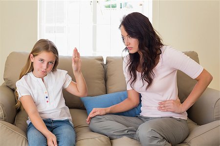 Stubborn girl showing stop gesture to mother while sitting on sofa at home Stock Photo - Budget Royalty-Free & Subscription, Code: 400-07341875