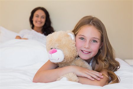 small little girl pic to hug a teddy - Portrait of little girl embracing teddy bear with mother in background at home Stock Photo - Budget Royalty-Free & Subscription, Code: 400-07341945