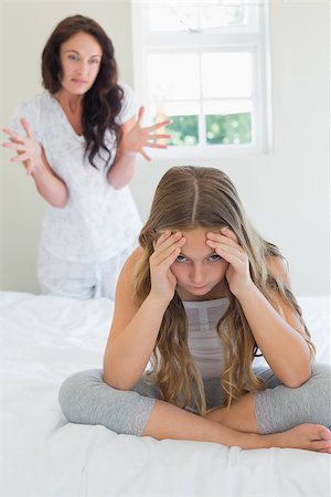 Irritated girl sitting in bed while mother scolding her in background at home Stock Photo - Budget Royalty-Free & Subscription, Code: 400-07342079