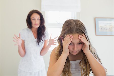 Frustrated girl sitting in bed while mother scolding her in background at home Stock Photo - Budget Royalty-Free & Subscription, Code: 400-07342080