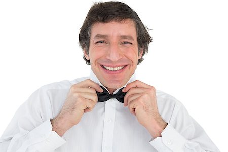 Portrait of happy groom adjusting bow tie over white background Stock Photo - Budget Royalty-Free & Subscription, Code: 400-07342325