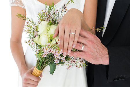 simsearch:400-04950359,k - Mid section of newly wed couple with flower bouquet showing wedding rings over white background Stock Photo - Budget Royalty-Free & Subscription, Code: 400-07342439